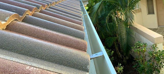 Metal gutter system installed along a tile roof edge to direct rainwater away from the home and protect landscaping