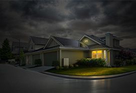 Suburban home illuminated at night under dark storm clouds, highlighting exterior lighting and roofline