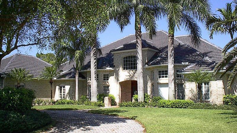 Tile roof home with palm trees in yard