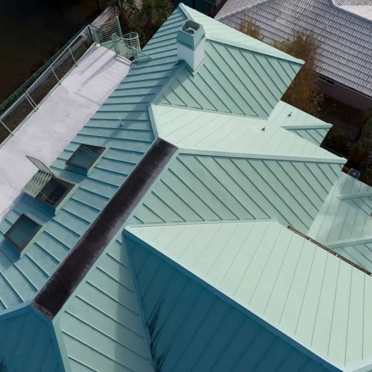 Aerial view of a standing seam metal roof with multiple hips, valleys, and roof penetrations on a residential home